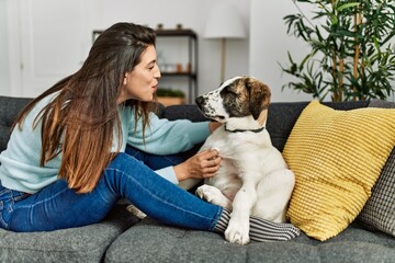 Young woman hugging dog sitting on sofa at home