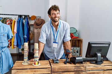 Young hispanic shopkeeper man smiling happy working at clothing store.