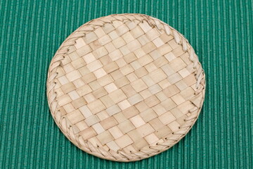 detail of wicker coasters on green tablecloth