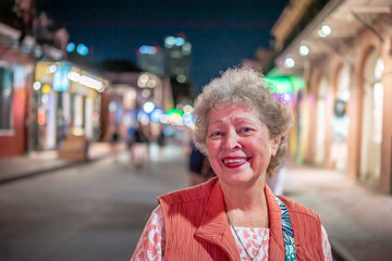 A beautiful senior woman enjoys exploring Bourbon Street in the French Quarter at night.