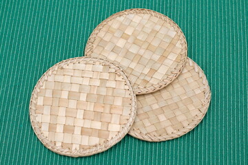 detail of wicker coasters on green tablecloth