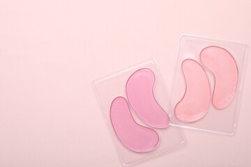Packages with under eye patches on light pink background, flat lay. Space for text