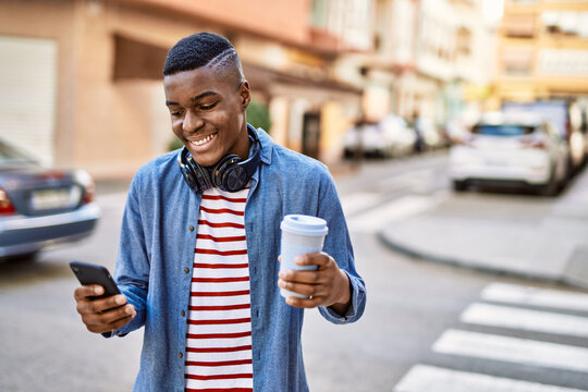 Young african american man using smartphone drinking coffee at the city.