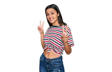Obraz premium Young hispanic girl wearing casual clothes smiling looking to the camera showing fingers doing victory sign. number two.