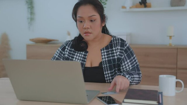 A large, plump, chubby Asian Female ordering online by paying via credit card payment system. The woman was disappointed that she was unable to reserve the items she needed. online shopping concept.