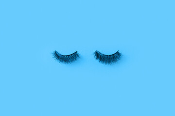 Creative blue Monday concept. Glued eyelashes on a blue wall.