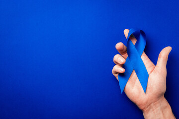 Prostate care. Awareness prostate cancer of men health in November. Blue ribbon in hands isolated...