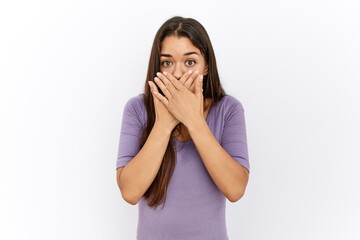 Young brunette woman standing by isolated background shocked covering mouth with hands for mistake. secret concept.