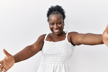 Young african woman standing over white isolated background looking at the camera smiling with open...