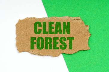 On a white-green background lies a piece of cardboard with the inscription - Clean forest