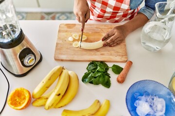 Hispanic brunette woman preparing fruit smoothie at the kitchen