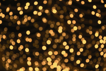 Festive blurred gold defocused garland on black background. City night light blur bokeh. Christmas...