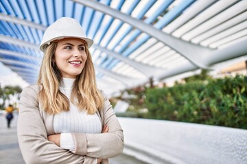 Young blonde woman smiling confident wearing hardhat at street