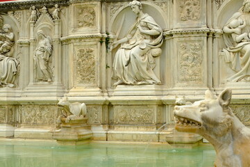 Fototapeta na wymiar Public fountain. Fonte Gaia fountain in Siena.Reliefs carved in marble on originals by Jacopo della Quercia in Piazza del Campo. Siena, Tuscany, Italy.