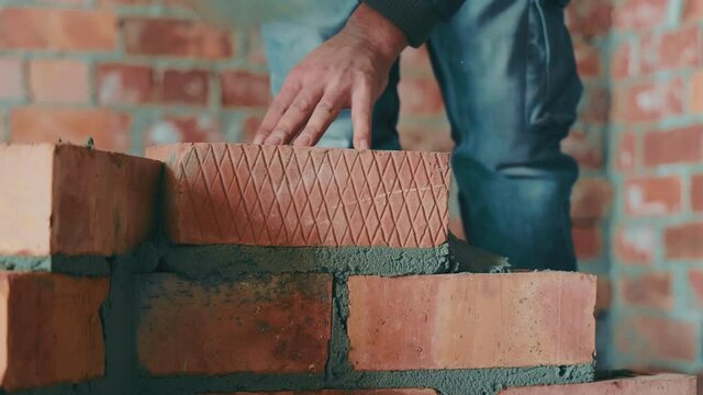 Masters lay bricks and build the wall of the house. Construction work on construction. Construction of interior partitions from red brick.