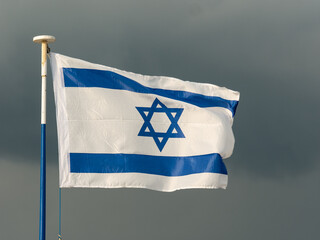 Israeli flag flutters in the wind, dark sky in background - 469151571