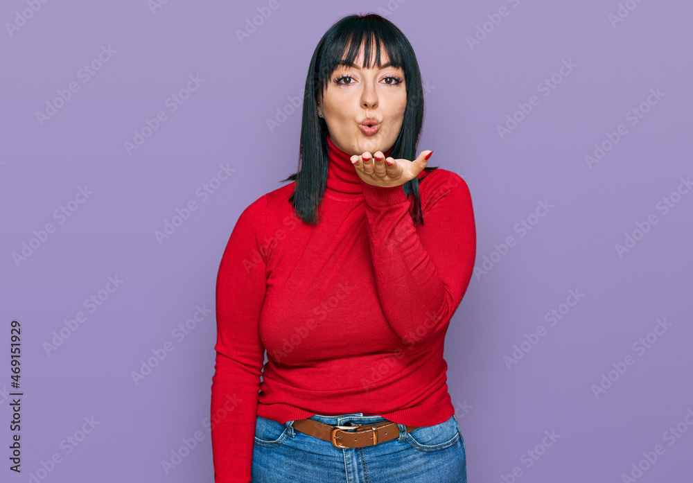 Poster Young hispanic woman wearing casual clothes looking at the camera blowing a kiss with hand on air being lovely and sexy. love expression.