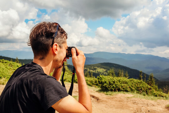 Photographer taking pictures of Carpathian mountains landscape. Man using camera to make photos and footage