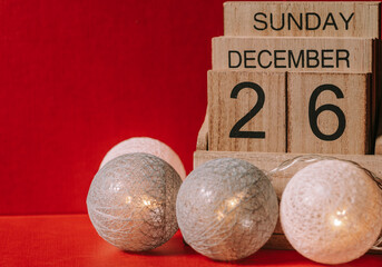 Festive wooden calendar of December 26th 2021 years Sunday on red background.