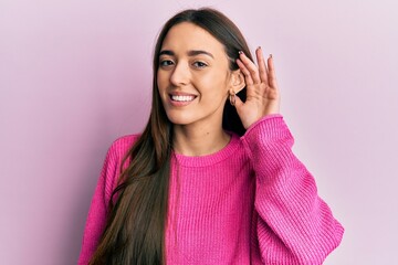Young hispanic girl wearing casual clothes smiling with hand over ear listening and hearing to rumor or gossip. deafness concept.