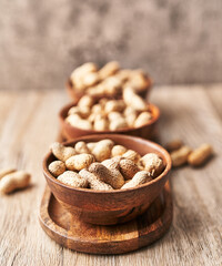  Bowls of peanuts with shell on a wooden surface