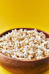  Bowl of salty popcorns on a yellow background