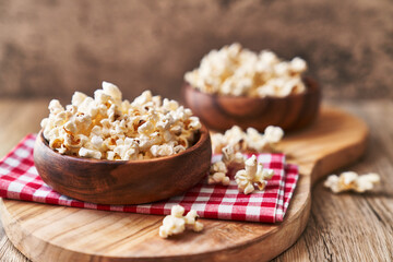  Bowls of salty popcorns on a wooden surface