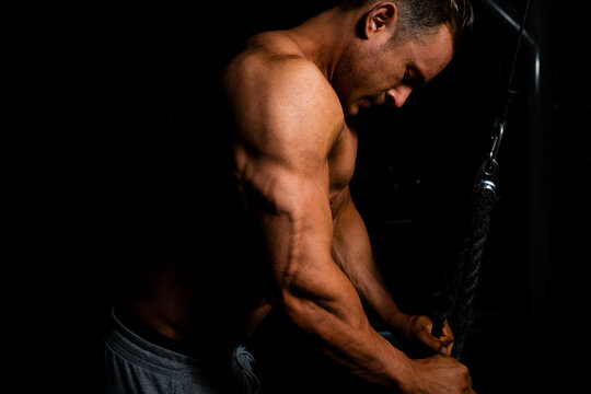 Junger Bodybuilder beim Trizeps Training mit dem Seilzug im GYM