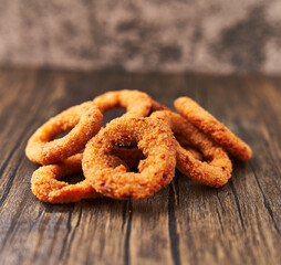  Bunch of breaded onion rings on a wooden surface