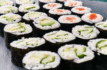  Group of avocado, salmon and cucumber sushi makis on a concrete surface