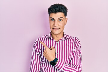 Young hispanic man wearing casual clothes pointing aside worried and nervous with forefinger, concerned and surprised expression