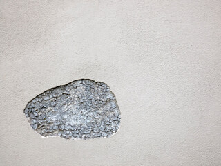 A piece of plaster on the wall has fallen off and a stone wall is visible