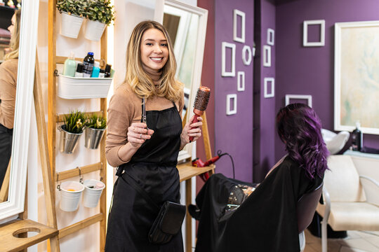 Beautiful hairstyle of young adult woman with purple hair in hair salon.