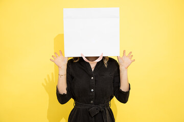 Photo of unrecognizable woman stands with shopping bag on head, stress relief with shopping, shopaholic, female psychology, studio portrait on yellow background.
