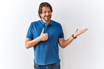 Handsome middle age man standing together over isolated background showing palm hand and doing ok gesture with thumbs up, smiling happy and cheerful