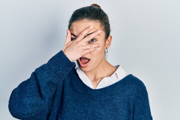 Young caucasian girl wearing casual clothes peeking in shock covering face and eyes with hand, looking through fingers with embarrassed expression.