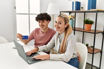 Young couple buying using laptop and credit card at home.