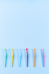 Different size interdental brush angles on blue background, vertical, copy space