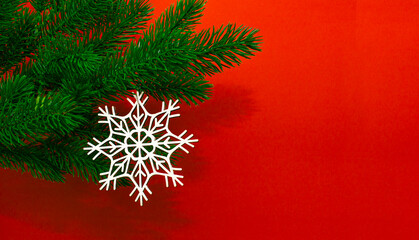 Christmas tree green branch with wooden craft toy. White snowflake on red background, zero waste concept