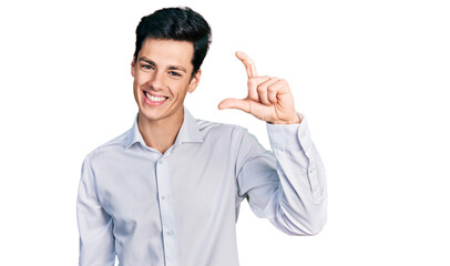 Fototapeta premium Young hispanic business man wearing business clothes smiling and confident gesturing with hand doing small size sign with fingers looking and the camera. measure concept.