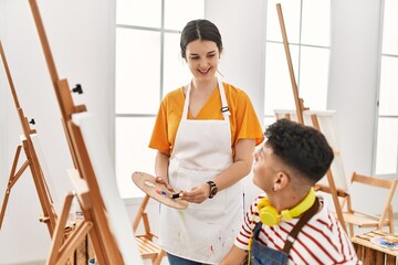 Student and teacher smiling happy painting at art school.