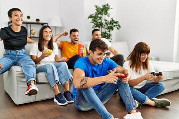 Obraz premium Group of young friends smiling happy playing video game at home.