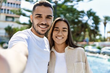 Obraz premium Young latin couple smiling happy and hugging making selfie by the camera at the city.