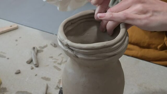 an unrecognizable ceramic creative woman working with a pottery wheel in a cozy workshop, making a vase or one, a craft pottery class