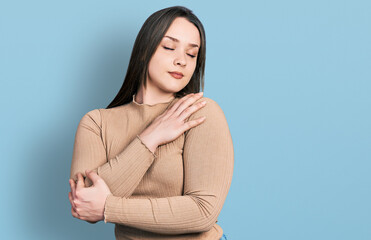 Obraz premium Young hispanic woman wearing casual clothes hugging oneself happy and positive, smiling confident. self love and self care