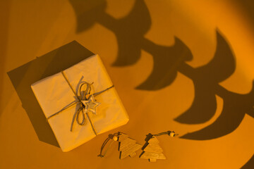 Christmas at sunset. Eco gift, wooden decorations and tree shadow in warm orange light. Top view