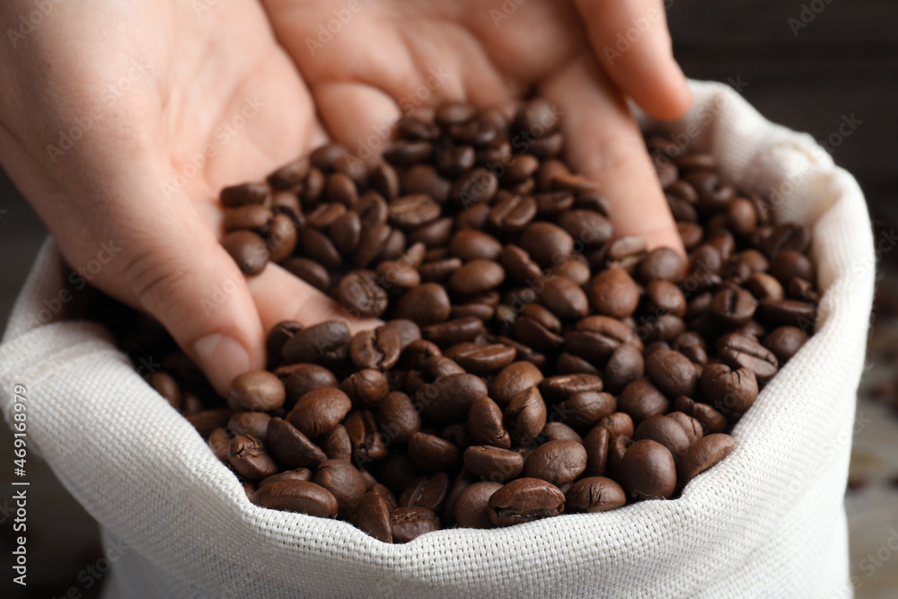 Wall mural woman taking roasted coffee beans from bag, closeup