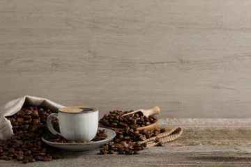 Printed kitchen splashbacks Cafe Cup of aromatic hot coffee and beans on wooden table, space for text