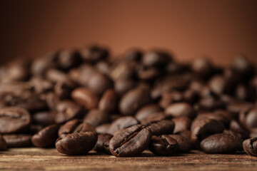 Many roasted coffee beans on wooden table, closeup