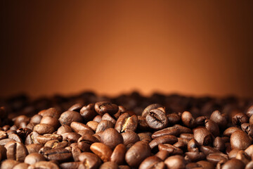 Heap of aromatic roasted coffee beans on brown background, closeup